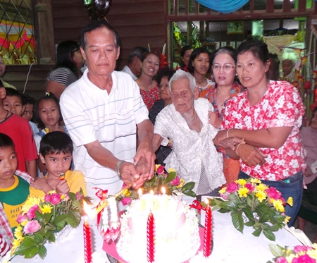 Friends and family help Rhan Lonlua light the candles on her 100th birthday cake.