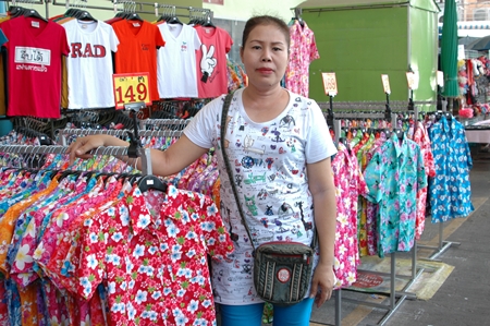 Somjit Sodkhomkhum, a clothing saleswoman serving New Naklua Market vendors, poses with some of her stock.