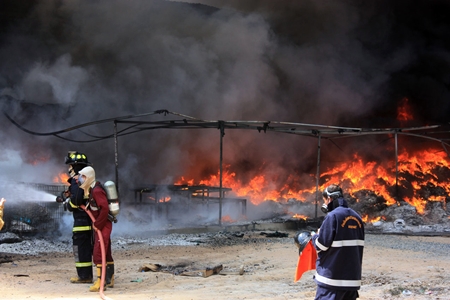 Fire police battle the inferno at the Master Glove Industries Co. plant in Pluakdaeng.