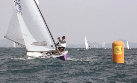 An OK Dinghy prepares to tack around a marker buoy.