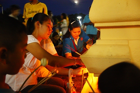 Citizens light candles and incense before the Wien Thien ceremony around the Bhodhisamphan temple hall.