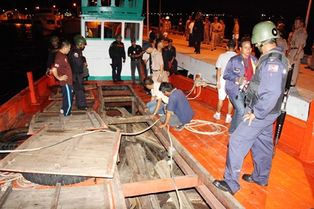 Officials inspect the smuggled rosewood found in the fish holds of this Cambodian fishing boat.