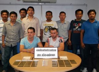 Police gather around the two Bulgarian suspects apprehended for allegedly using fake ATM cards to loot bank machines in Pattaya.