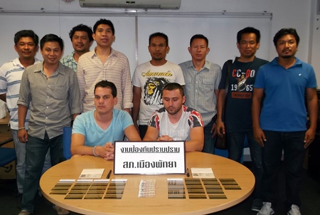 Police gather around the two Bulgarian suspects apprehended for allegedly using fake ATM cards to loot bank machines in Pattaya.