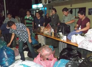 Copyright police sift through bags of counterfeit name-brand clothes and accessories after a raid of the Windy market on Beach Road.