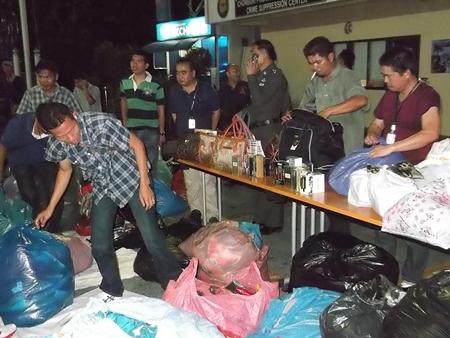 Copyright police sift through bags of counterfeit name-brand clothes and accessories after a raid of the Windy market on Beach Road.
