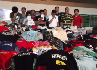 Police bring the suspects out for the media, along with the confiscated merchandise.