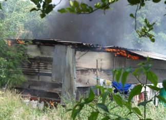 Flames peak through the roof of shacks used by Cambodian construction workers in Rayong.