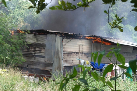 Flames peak through the roof of shacks used by Cambodian construction workers in Rayong.