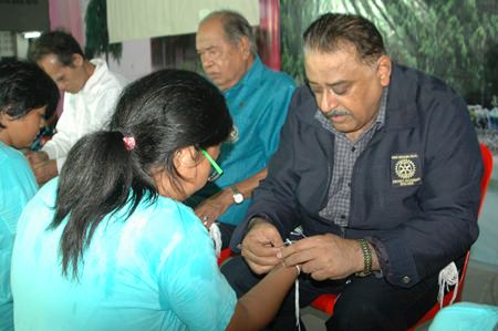 PDG Peter Malhotra joins Rotary leaders in tying sai-sin around the wrists of the Interact Club of Banglamung Schools new committee.