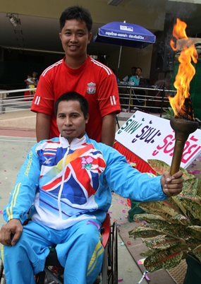 Paralympian powerlifter Narong Kaesanan carries the flame to start the games.