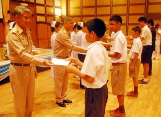 Queen Sirikit Naval Medical Center Deputy Director Vice Adm. Chumpol Thienchai hands out scholarships to children of government employees and navy personnel.