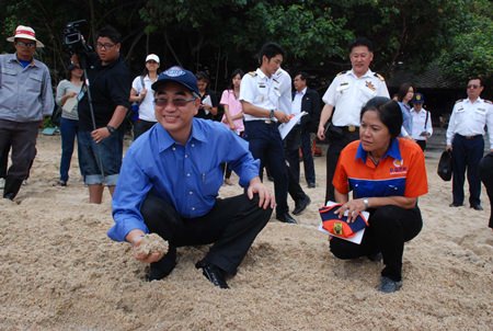 Natural Resources and the Environment Minister Vichet Kasemthongsri smiles as he checks the sand for a photo op on Ao Phrao beach.