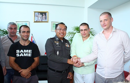 Capt. Samruay Saman (center), deputy suppression inspector for Chonburi Immigration, shakes hands with Illia Miasnikov (2nd right), Security Advisor at the Russian Convenience Center, as other Russians look on.