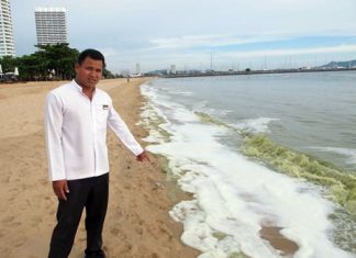 A local hotel employee points out the green slick that washed up on a Sattahip Beach.