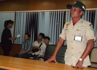 San Nongyai (standing) and his drunken “gang” (seated, background) have been charged with weapons, drugs and other offenses.