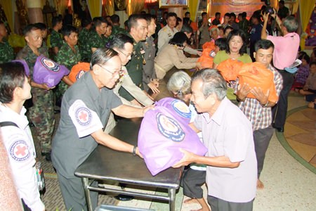 Civil servants, police and military personnel hand out bags of relief supplies from HRH Princess Soamsawalee’s Princess Pa Foundation for victims of flooding in Phanat Nikhom.