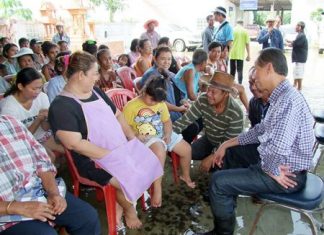 Chonburi Gov. Khomsan Ekachai (seated right) meets with local residents whilst sitting in flood waters during his tour of the province.
