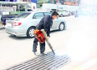 Officials from Pattaya’s Public Health Department spray mosquito pesticide into the drains on Pattaya 2nd Road.