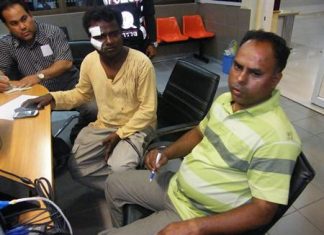 Karthikeyan Krishnan (center) and Kadher Basha (right) file a report with police about their being kidnapped and robbed.