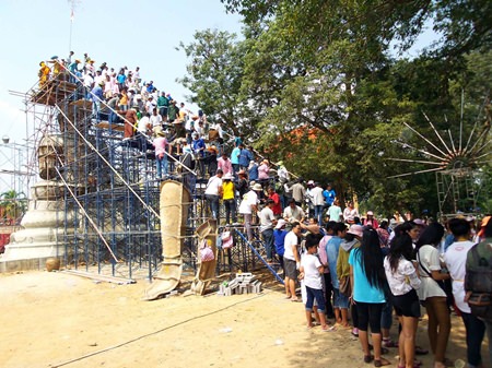 People form a bucket brigade to bring cement and precious items to be put on top of the new Buddha statue in Rayong.