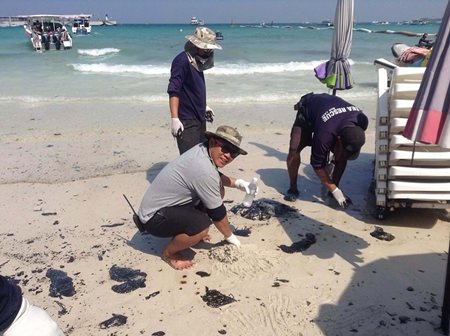Rescue workers clean up oil deposits from at Koh Larn’s Tawan Beach.