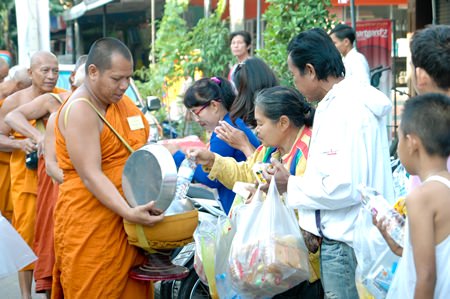 People in Naklua line up alongside the road to present alms to monks who ordained in honor of HM the King’s 86th birthday.