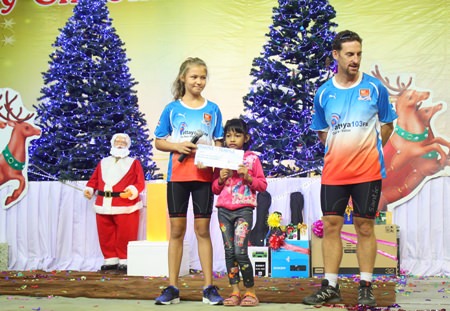 (Above) Poppy Mulford and her dad, Nathaniel Mulford, both of whom this past Fall completed a charity bicycle ride from Ayutthaya to Angkor Wat, donate funds they raised to Yok, a pupil at the Sotpattana School for the Deaf, to help the young Thai girl have the operation she needs to restore her hearing.