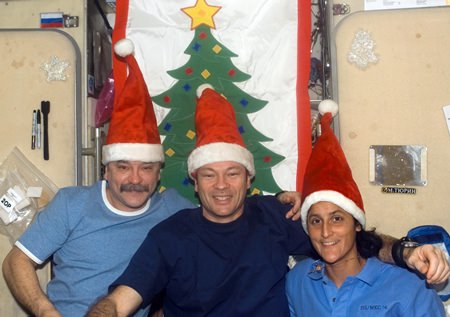 Wearing Santa Claus hats, cosmonaut Mikhail Tyurin (left), Expedition 14 flight engineer representing Russia’s Federal Space Agency; astronaut Michael E. Lopez-Alegria, commander and NASA space station science officer; and astronaut Sunita L. Williams, flight engineer, pose for a holiday photo in the Zvezda Service Module of the International Space Station.