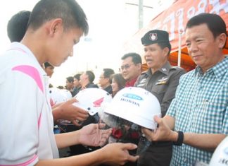Banglamung District Chief Sakchai Taengho (right), along with Col. Col. Supachai Phuikaewkhum (2nd right) distribute motorcycle helmets to students.