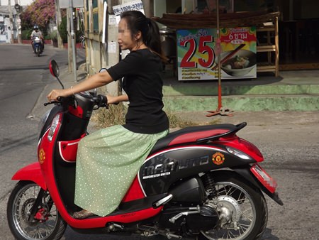 A woman rides her motorbike without a helmet on Central Pattaya Road.