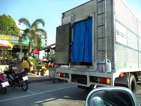 An ice truck double parks and holds up the traffic while the provided parking area was vacant and only a short distance away.