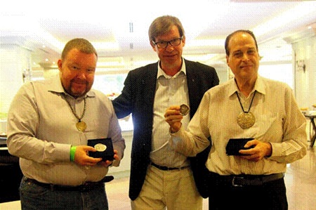 I.A.P.N. member Vasilijs Mihailovs (left) and Ronachai Krisadaolarn (right) stand with Thai coinage expert Jan Olav Aamlid (center) at the award ceremony in Bangkok.  Mihailovs and Krisadaolarn are displaying their I.A.P.N. book prize medals.