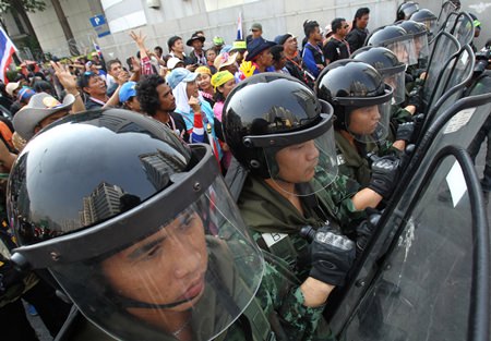 Thai soldiers stand guard to block anti-government protesters, left, during a rally outside the office of the permanent secretary for defense where Prime Minister Yingluck Shinawatra was reportedly working inside Monday, Feb. 3, in Bangkok. Around the country, the vast majority of voting stations were open and polling proceeded relatively peacefully, but the risk of violence remained high a day after gun battles in Bangkok left seven people wounded. Meanwhile, protesters vowed Monday to stage larger rallies in central Bangkok and push ahead their efforts to nullify the results of elections that were expected to prolong a national political crisis.  (AP Photo/Sakchai Lalit)
