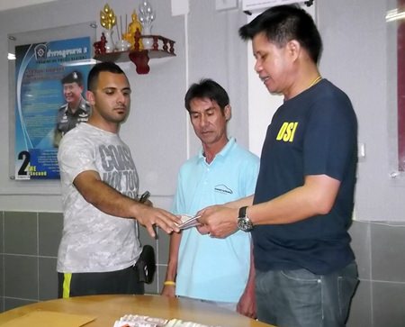 (L to R) Ramin Rajaeetabar receives his money and wallet back from taxi driver Wichian Phonkhong, overseen by Pattaya Police Superintendent Col. Supachai Puikaewkam.