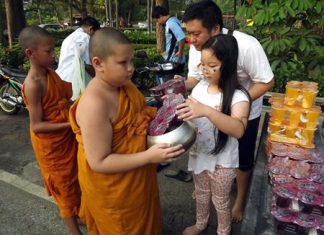 A father leads his daughter to offer alms.