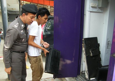 Suspect Athit Sangprasert shows police how he allegedly helped steal millions of baht from a Pattaya automated-teller machine.