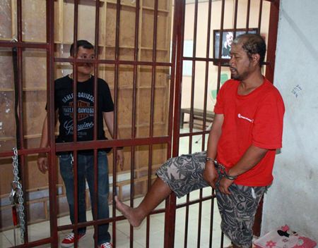 Somyos Anumat (right) shows police how he kicked open the cell door and nearly escaped.