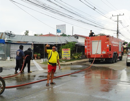 Pattaya’s Engineering Department uses high powered water spray to clean off sand dropped by soil-delivery trucks in front of Suttawas Temple.