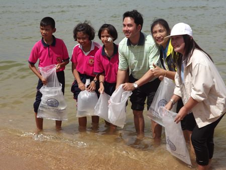 Mayor Itthiphol Kunplome (center) helps release 2,000 silver perch into the sea for World Environment Day.