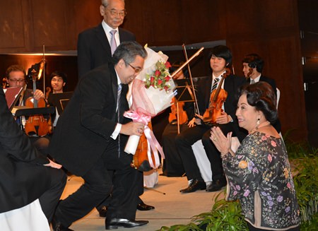 Siam Bayshore owner Kamala Sukosol (right) presents flowers of appreciation to soloist Siripong Tiptan while conductor H.E. Admiral M.L. Usni Pramoj looks on.