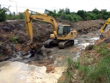 Sanitation Engineering Department workers continue to try and divert flood waters away from residential areas by digging a runoff ditch along the railroad tracks.
