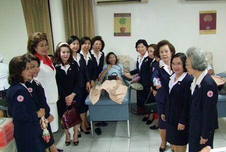 Red Cross members gather around to watch a benevolent person donate blood.