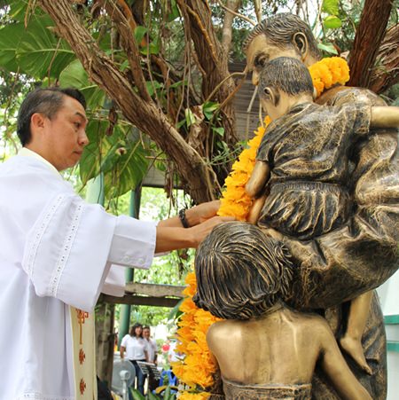 Father Peter lays a new garland on the statue of Father Ray.