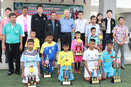 Youth players pose with their trophies in front of Pattaya Deputy Mayor Wattana Chantanawaranon (standing center) and other Pattaya City officials at the conclusion of the 2-week football tournament. 