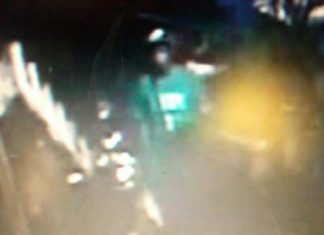 This blurry image, taken from security camera footage, shows a thin young man in a green shirt steeling a motorcycle.