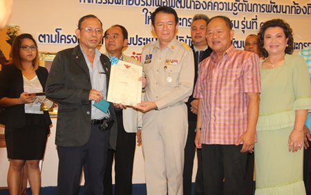 Likit Thailaemthong receives a certificate of appreciation from Banglamung District Chief Sakchai Taengho and Nongprue Mayor Mai Chaiyanit for donating land to Nongprue Municipality.