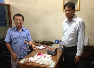 Korapat Teerapripruek (left), driver of Pattaya Transportation Cooperative bus No. 83, turns the lost handbag and its contents in to cooperative President Thawat Puagboonnak (right) at headquarters where it was later claimed by its rightful owner.