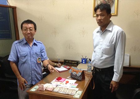 Korapat Teerapripruek (left), driver of Pattaya Transportation Cooperative bus No. 83, turns the lost handbag and its contents in to cooperative President Thawat Puagboonnak (right) at headquarters where it was later claimed by its rightful owner.