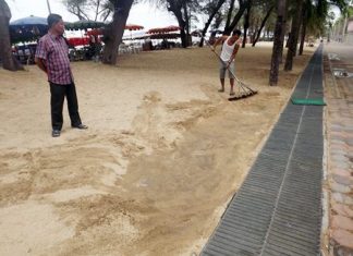 Beach vendors brush sand off the footpath to prove that it was all buried.